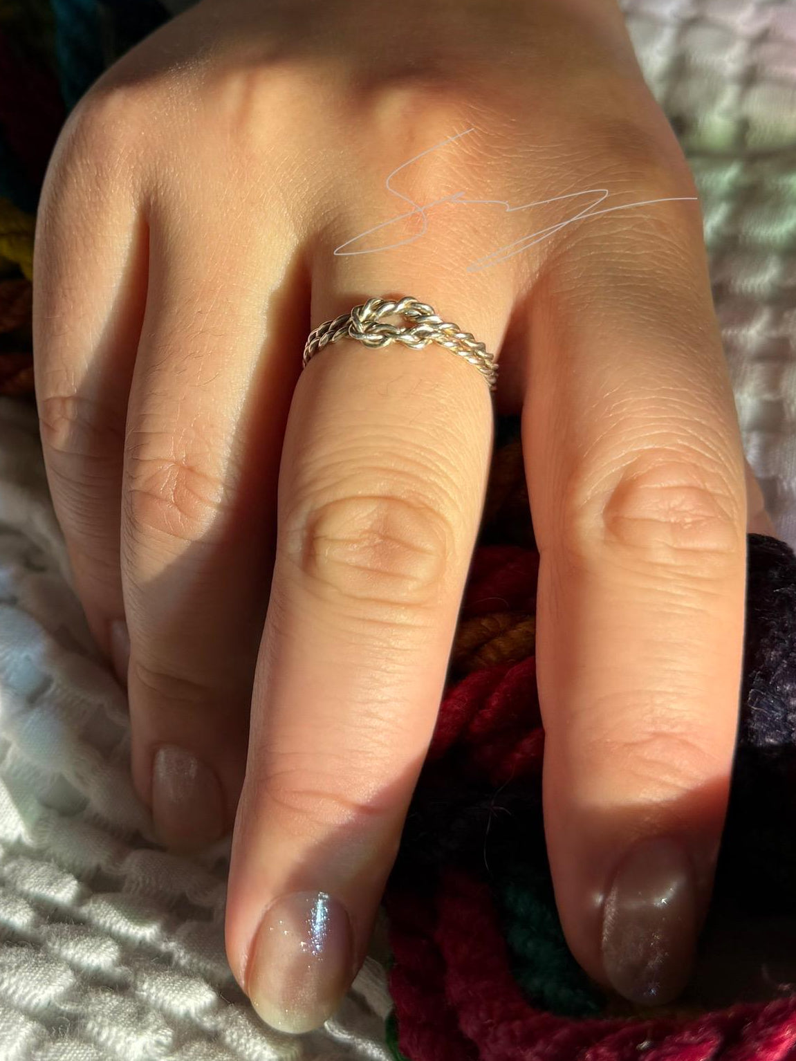 Hand wearing a ring with colorful rope in the background
