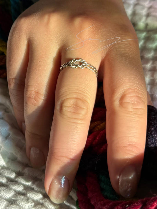 Hand wearing a ring with colorful rope in the background